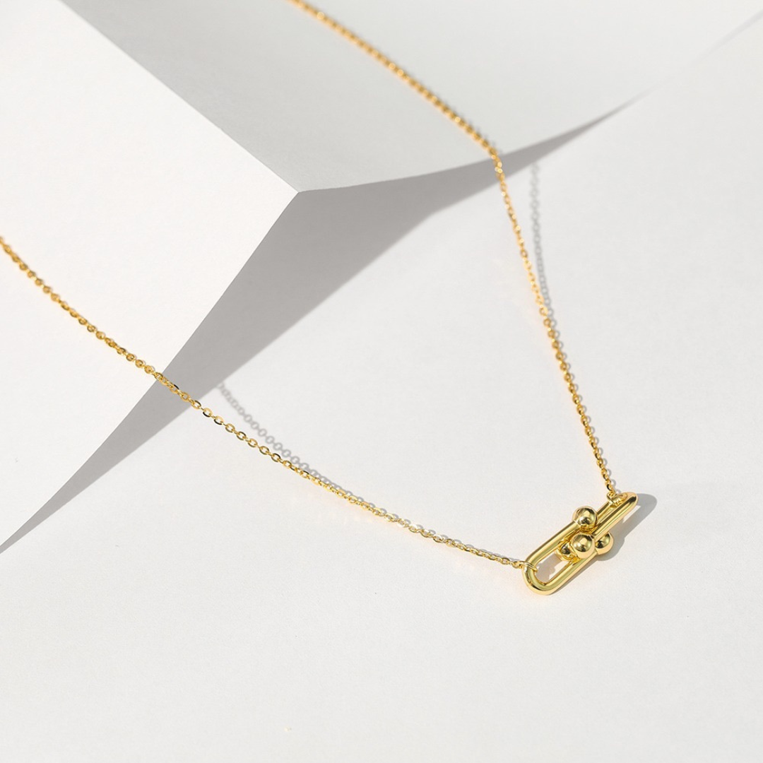 Gold Plated Link Pendant Necklace displayed on folded paper, highlighting the modern double-link and polished orb design