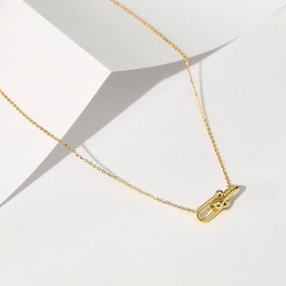 Gold Plated Link Pendant Necklace displayed on folded paper, highlighting the modern double-link and polished orb design