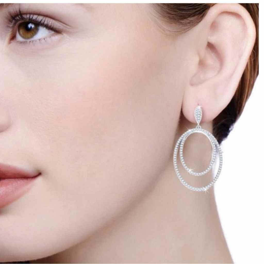 Lady wearing an oval within an oval earrings encrusted with CZ stones.