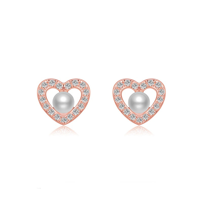 Rose gold love heart earrings with a pearl in the centre. The love hearts are encrusted in shiny cubic zirconia stones.